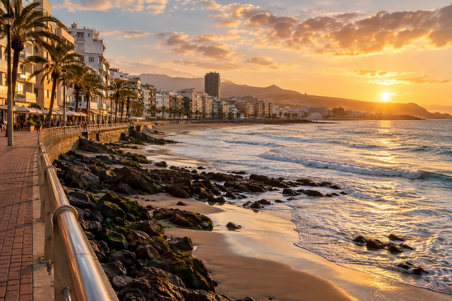 The beachside promenade at the southern end of Las Canteras with compact urban blocks, Atlantic surf and a natural view toward the waterfront